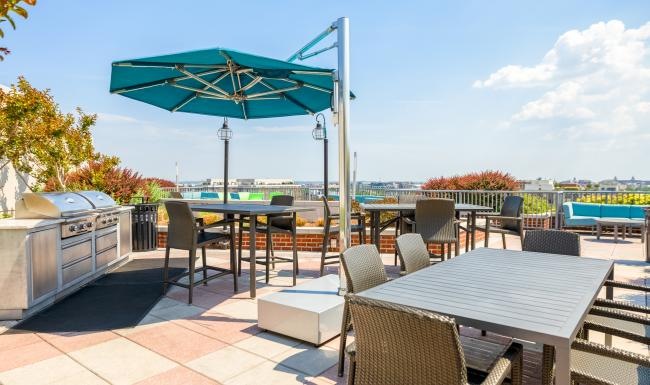 Quick access to state-of-the-art amenities a rooftop grill area with tables and chairs